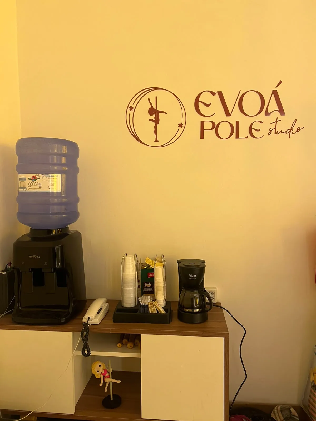 Cantinho do café da Evoá com o logo do estúdio na parede
